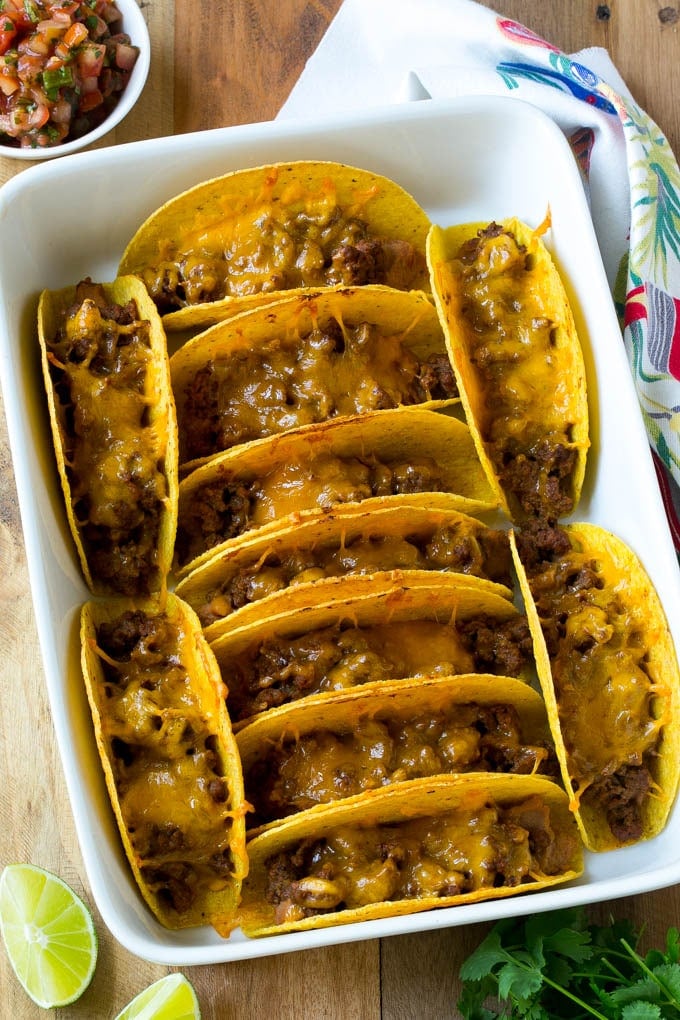 Baked beef tacos topped with melted cheese in a casserole dish.