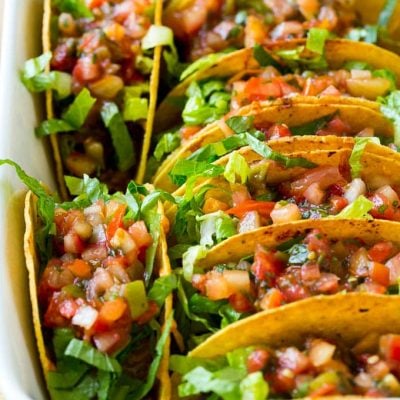 These oven baked beef tacos are filled with beans, meat and melted cheese, then topped off with shredded lettuce and fresh salsa. The best way to make tacos for a crowd!