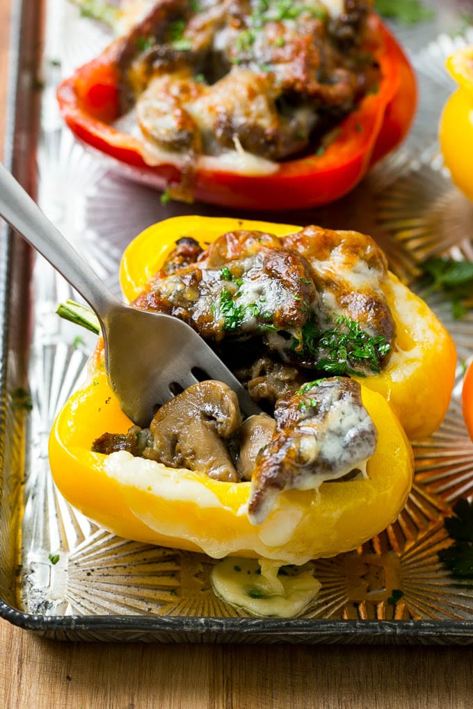 A fork in a Philly cheesesteak stuffed pepper that's filled with meat, cheese and mushrooms.