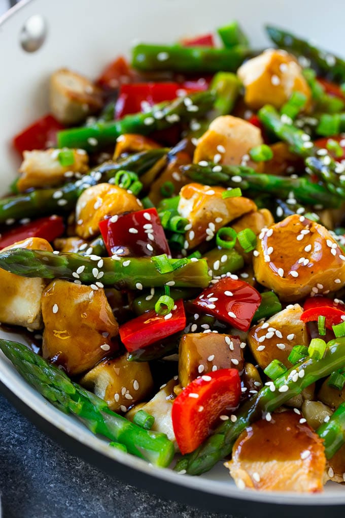 Teriyaki chicken with asparagus and red peppers in a frying pan.