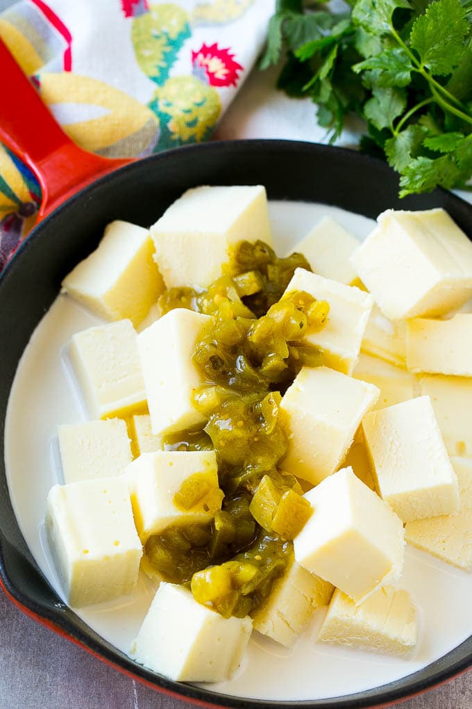 Cheese, salsa verde and half and half in a skillet to make white queso dip.