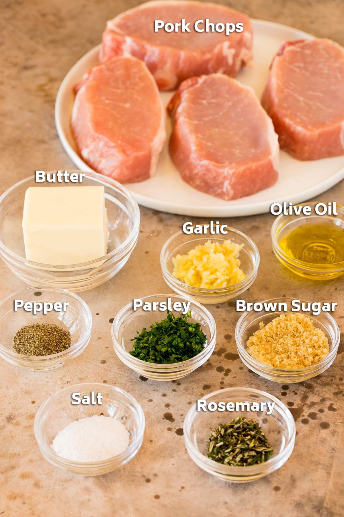 Ingredients including pork chops, garlic, butter, herbs and seasonings.