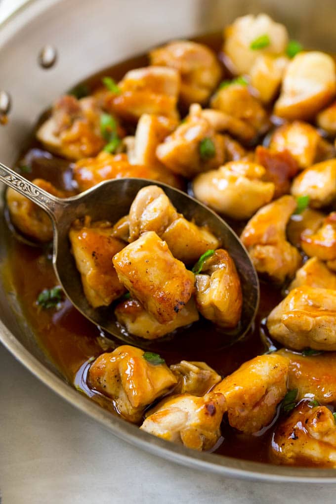 A pan of bourbon chicken with a serving spoon in it.