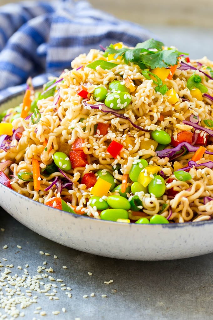 A mixture of ramen noodles, carrots, edamame, cabbage and peppers in a serving bowl.