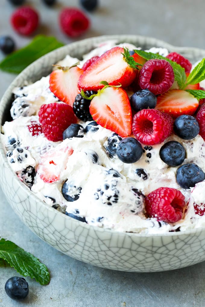 A serving bowl of berry cheesecake salad topped with blueberries, raspberries and strawberries.