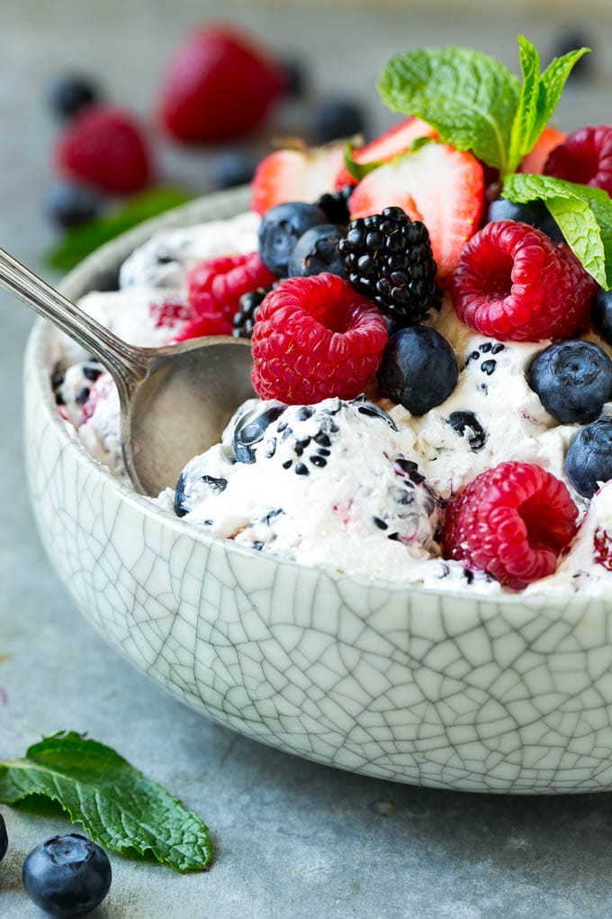 Berry cheesecake salad in a bowl garnished with fresh berries and mint.
