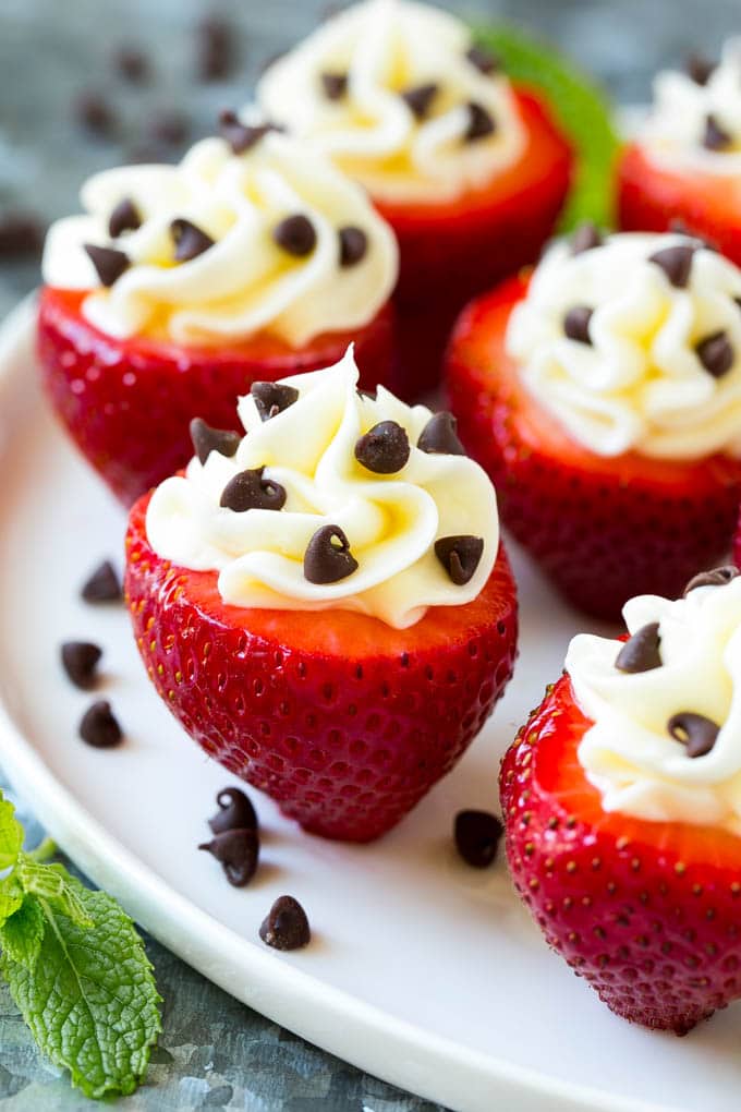 A plate of strawberries stuffed with cheesecake filling and chocolate chips.