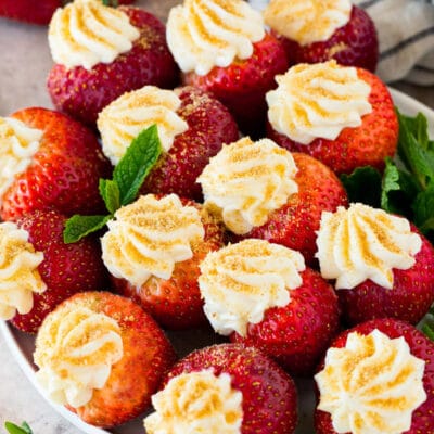 A plate of cheesecake stuffed strawberries garnished with fresh mint.