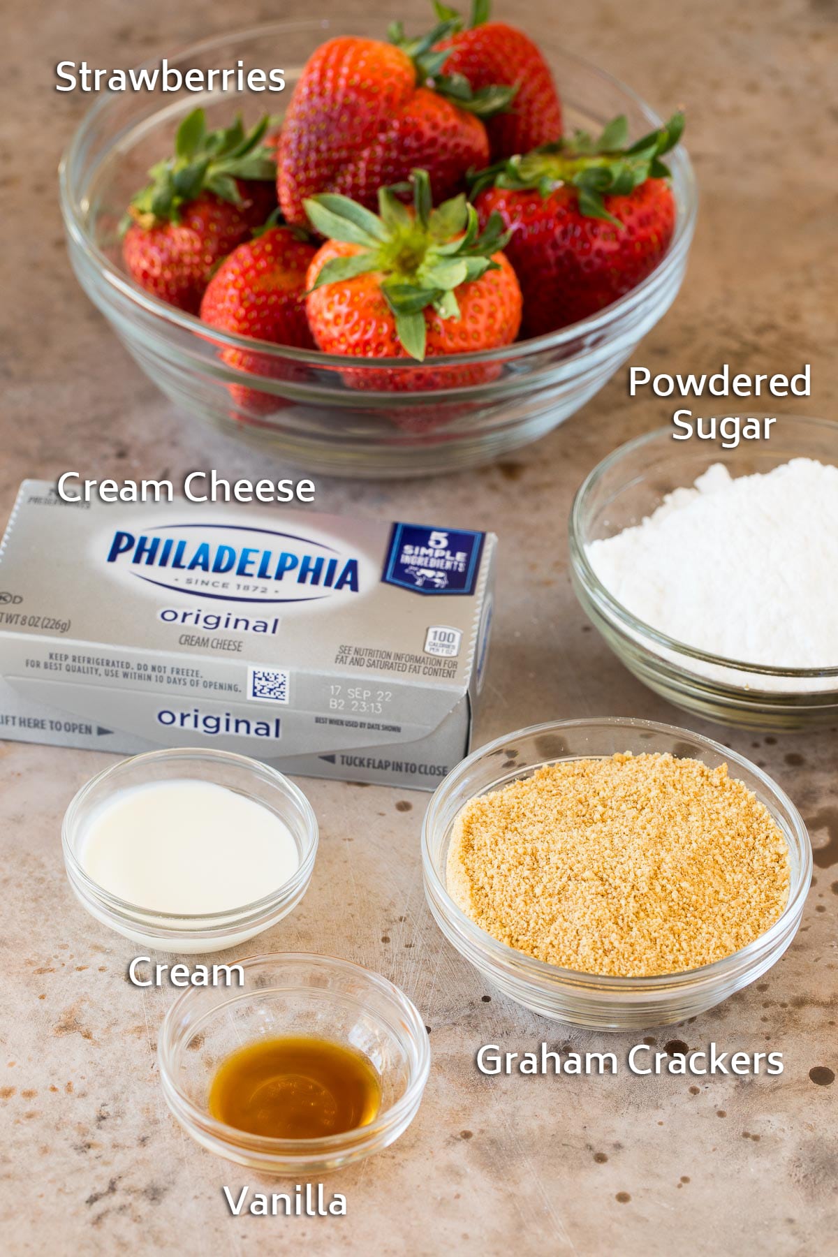 Ingredients including strawberries, cream cheese, sugar and graham cracker crumbs.
