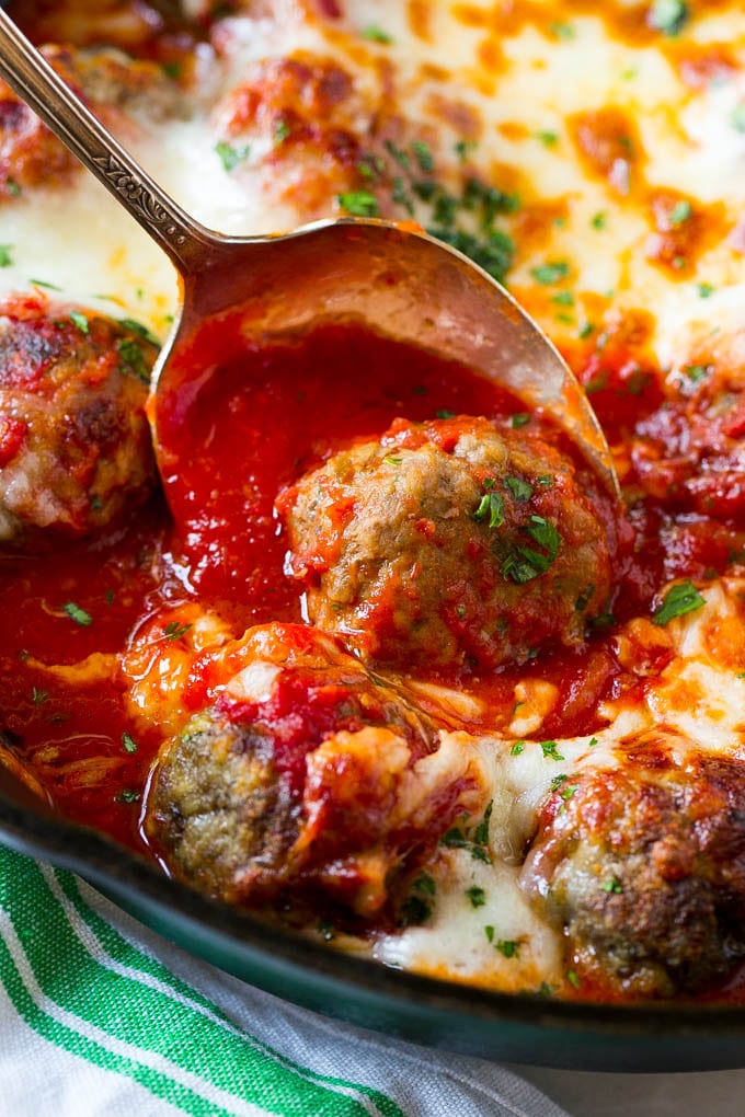 Baked meatballs in a skillet with tomato sauce and melted cheese.