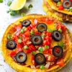 A Mexican pizza topped with cheese, tomatoes and olives.