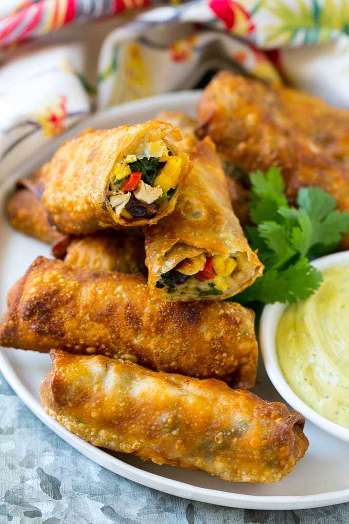 Egg rolls stuffed with diced chicken, bell peppers, black beans and cheese on a serving plate.
