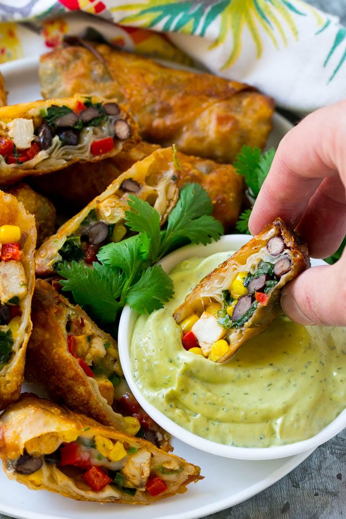 A southwestern egg roll being dipped into avocado sauce.