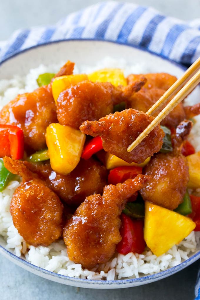 Sweet and sour shrimp being picked up with chopsticks.