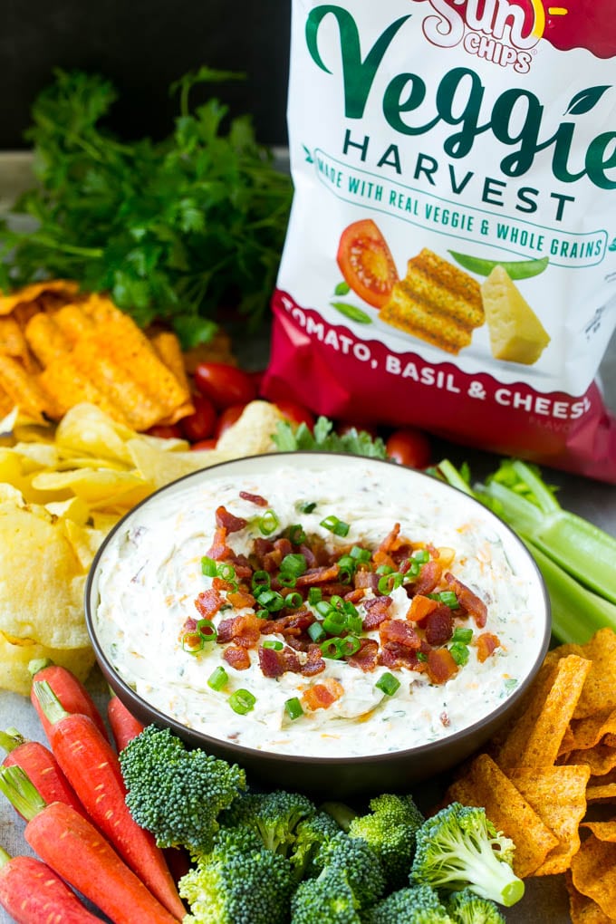 Bacon ranch dip in a bowl served with different types of chips and vegetables.