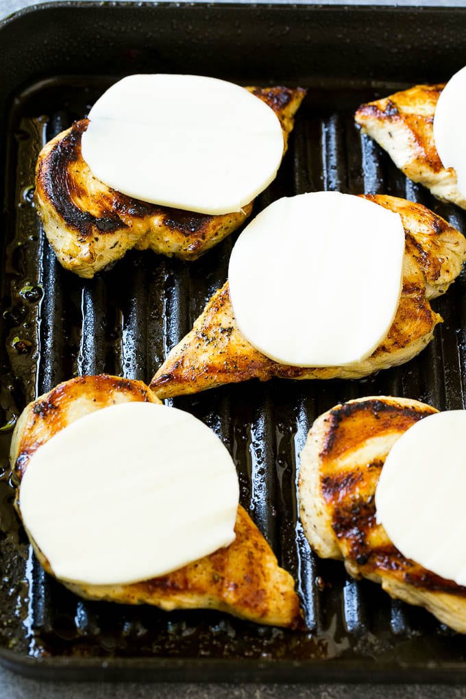 Grilled chicken with mozzarella cheese slices on top.