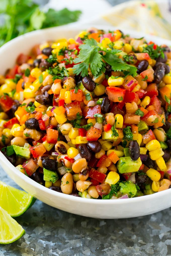 A bowl full of cowboy caviar made from finely diced vegetables, beans, black eyed peas and avocado.