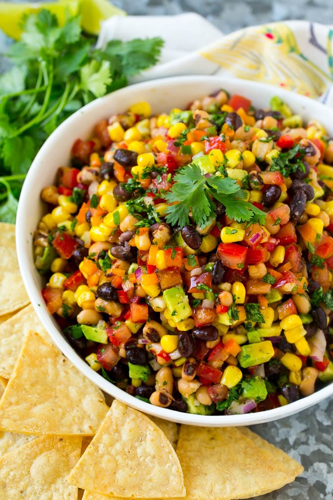 A bowl of cowboy caviar surrounded by tortilla chips.