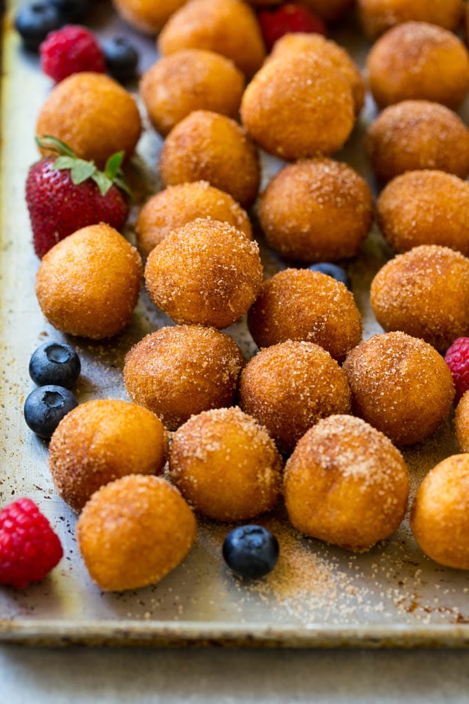 Cinnamon sugar donut holes on a tray surrounded by berries