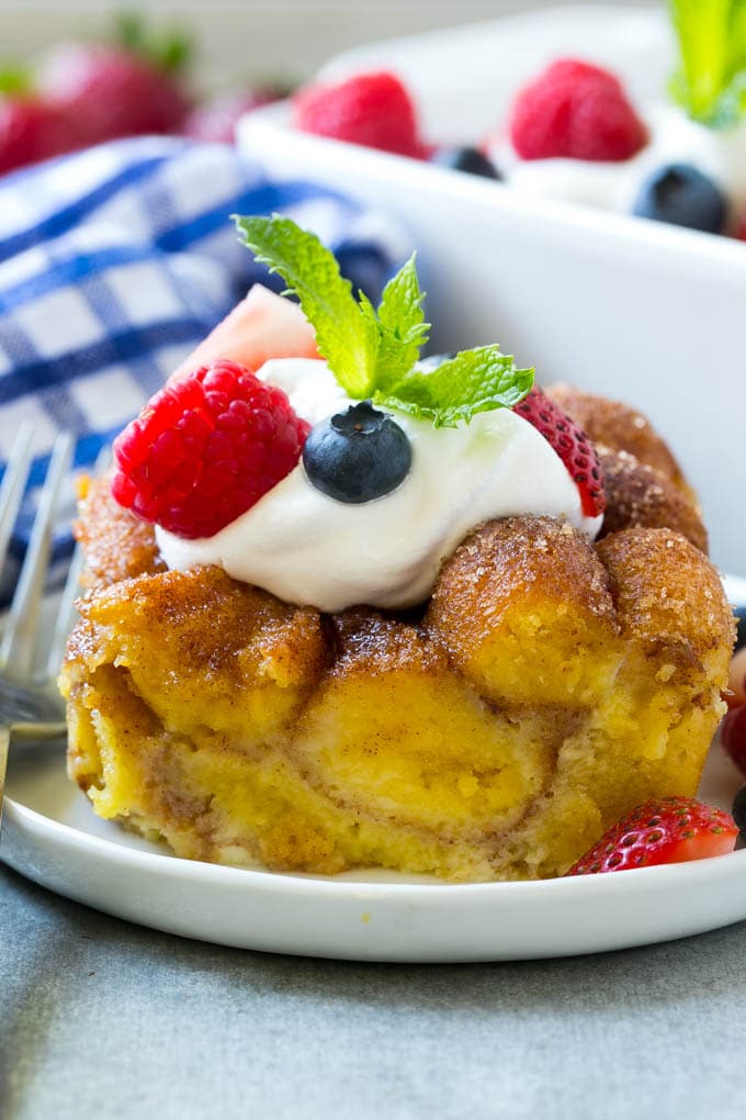 Slice of donut bread pudding topped with whipped cream and berries.