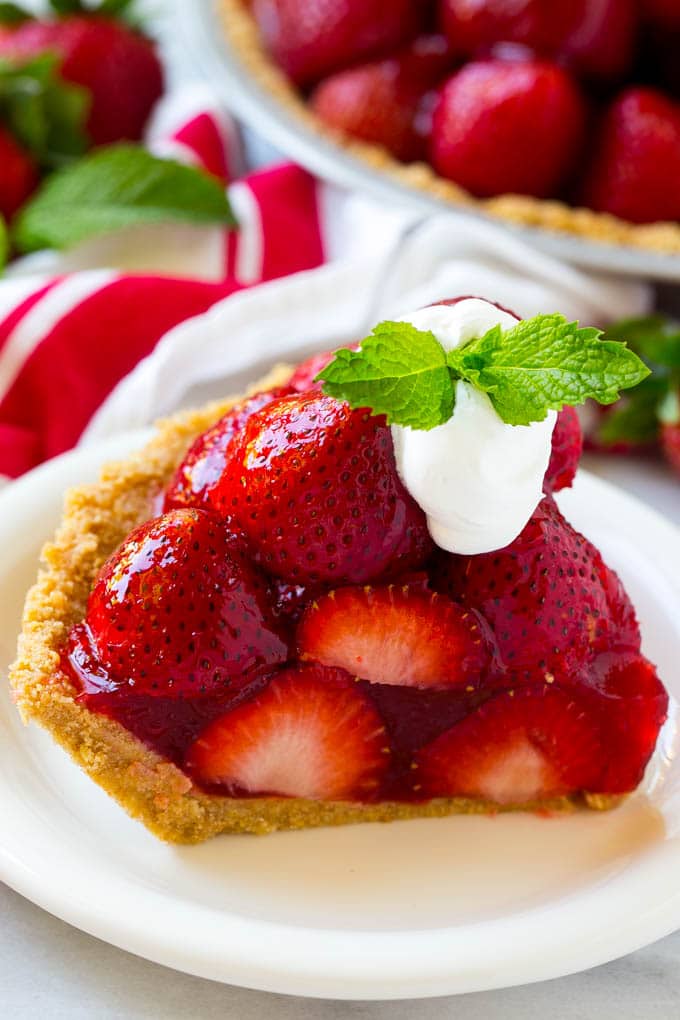 A slice of no bake fresh strawberry pie with whipped cream on top.