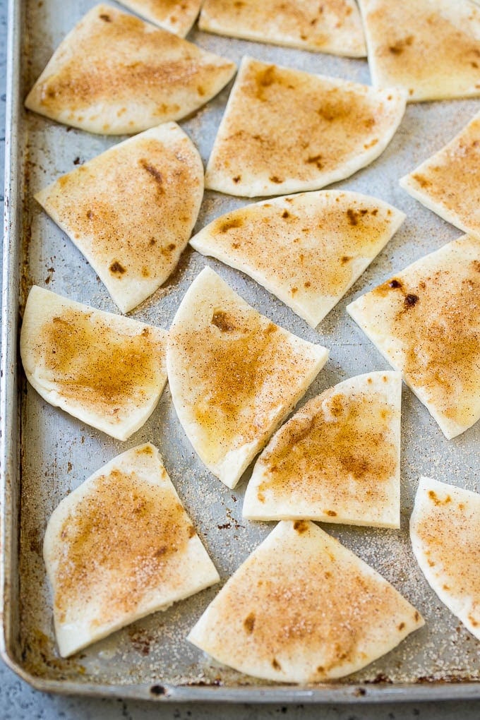 Tortilla wedges coated in cinnamon sugar on a baking sheet.