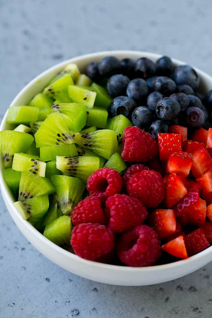 A bowl of raspberries, kiwi, strawberries and blueberries.