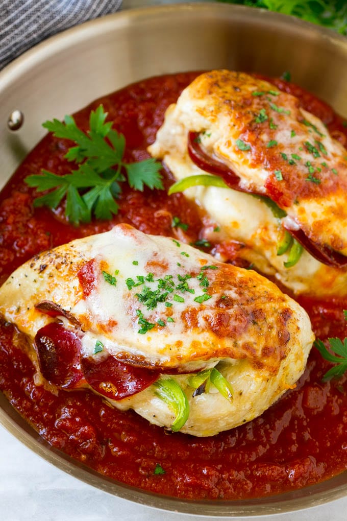 Two stuffed chicken breasts in a pan with tomato sauce and cheese.
