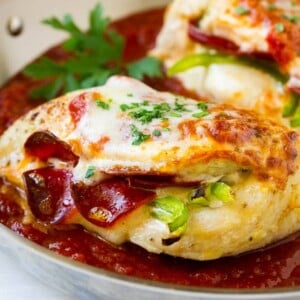 Chicken breasts stuffed with pepperoni and cheese in a pan of marinara sauce.