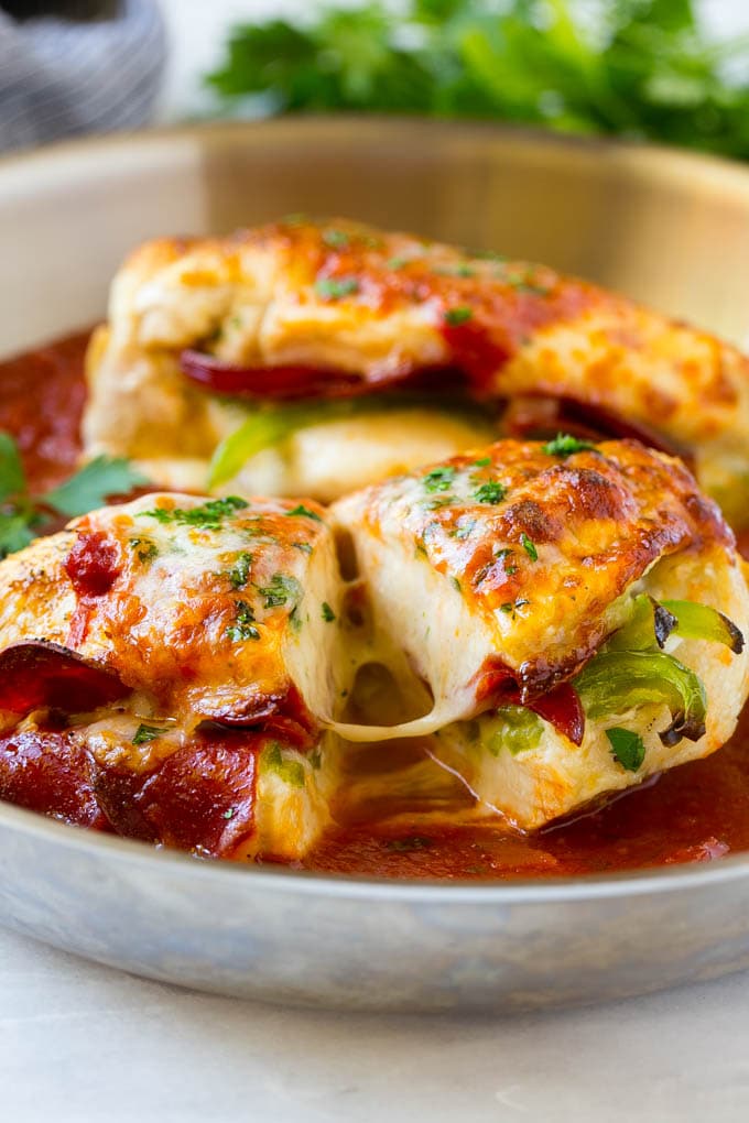 A pizza stuffed chicken breast cut in half in a pan