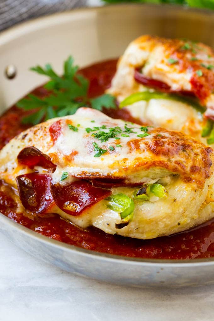 Pizza stuffed chicken breasts with pepperoni and cheese in a pan of marinara sauce.