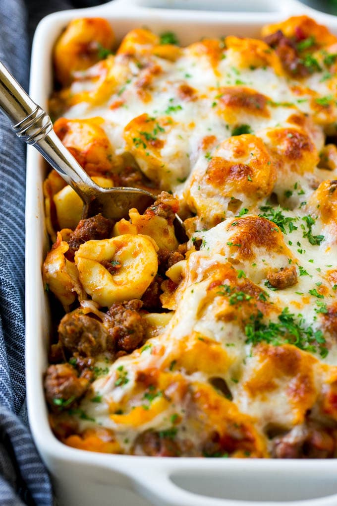 A pan of baked tortellini in a meat sauce, all covered with cheese.