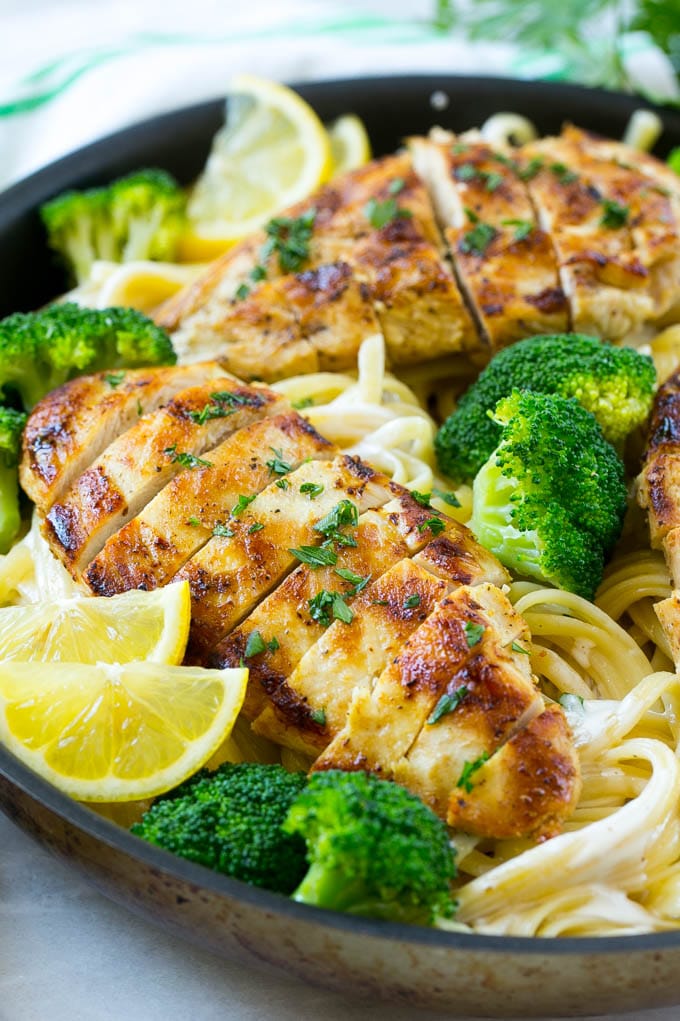 Sliced chicken breast with broccoli on top of creamy linguine pasta.