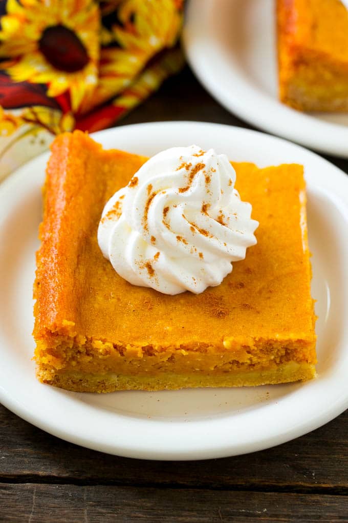 A slice of pumpkin gooey butter cake topped with whipped cream.