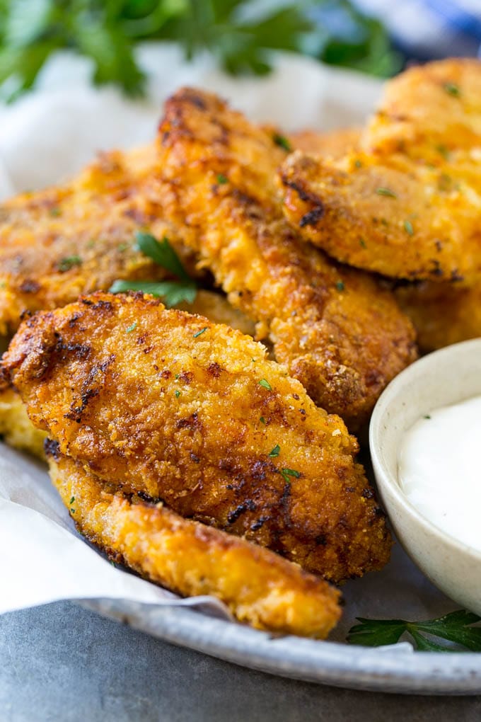 Baked oven fried chicken fingers in a dish with a side of ranch dressing.