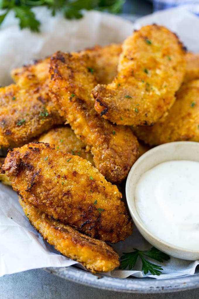 Crispy baked fried chicken fingers on a plate with ranch dip.