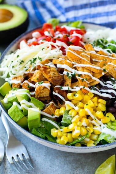 A bowl of BBQ chicken salad topped with a drizzle of ranch dressing.