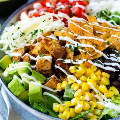 A bowl of BBQ chicken salad topped with a drizzle of ranch dressing.