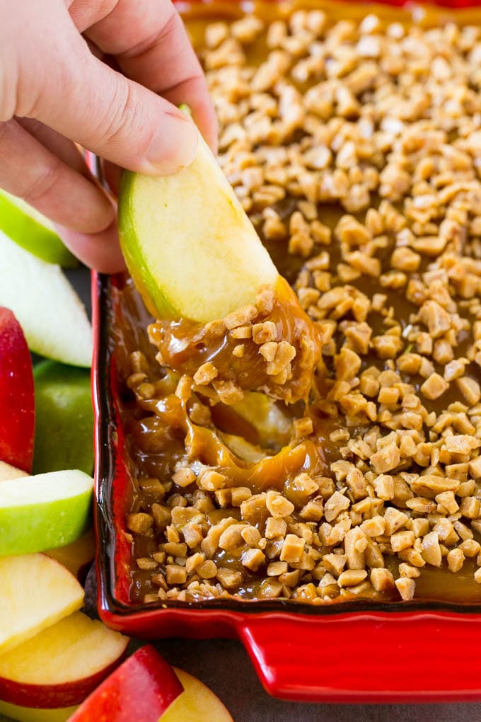 A hand scooping out a serving of caramel apple dip.