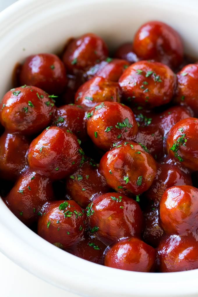 Cranberry meatballs in a crock pot topped with parsley.