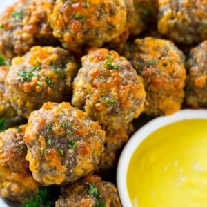 A platter of sausage cheese balls with honey mustard sauce for dipping.