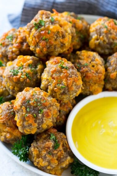 A platter of sausage cheese balls with honey mustard sauce for dipping.