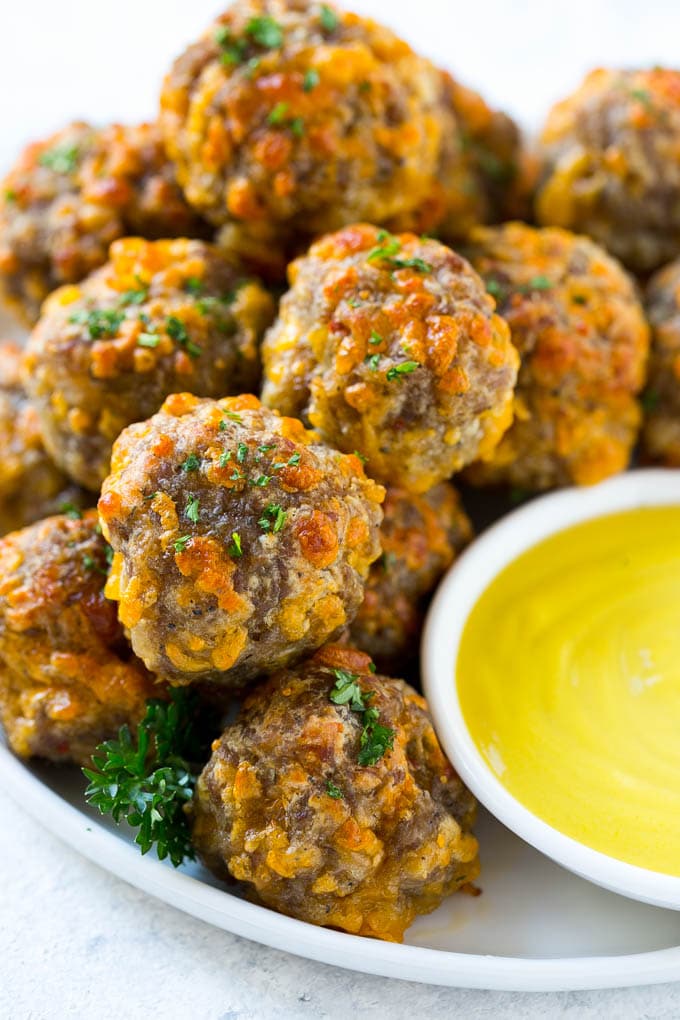A pile of sausage cheese balls with a side of honey mustard.