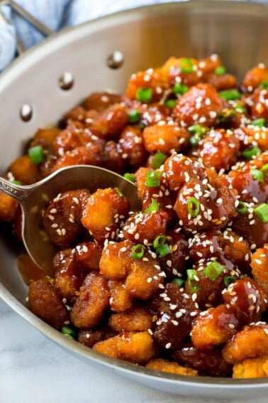 A pan of crispy sesame shrimp tossed in an Asian style sauce.