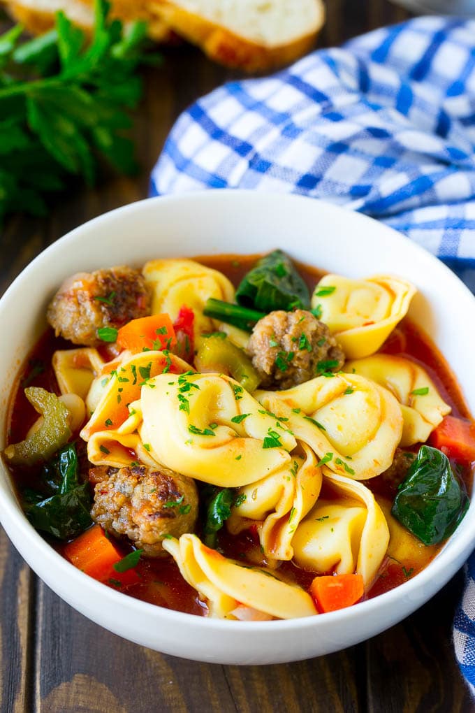 A bowl of tortellini soup with sausage and vegetables.