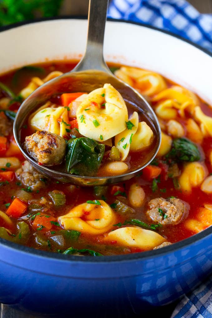 A ladle serving up a portion of tortellini soup.