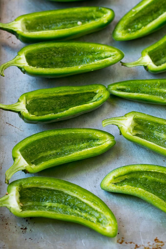 Halved and hollowed out jalapenos on a sheet pan.