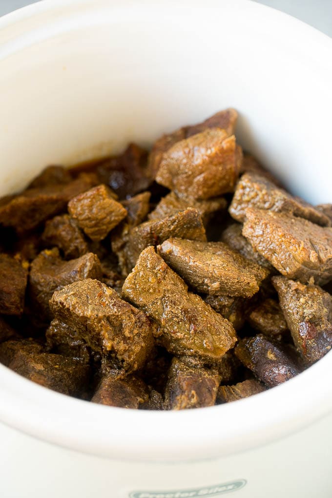 Cooked barbacoa cubes in a slow cooker.