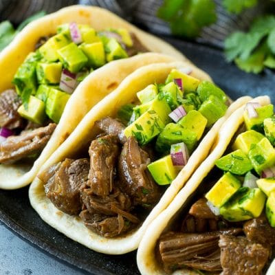 Slow cooker barbacoa tacos topped with avocado.