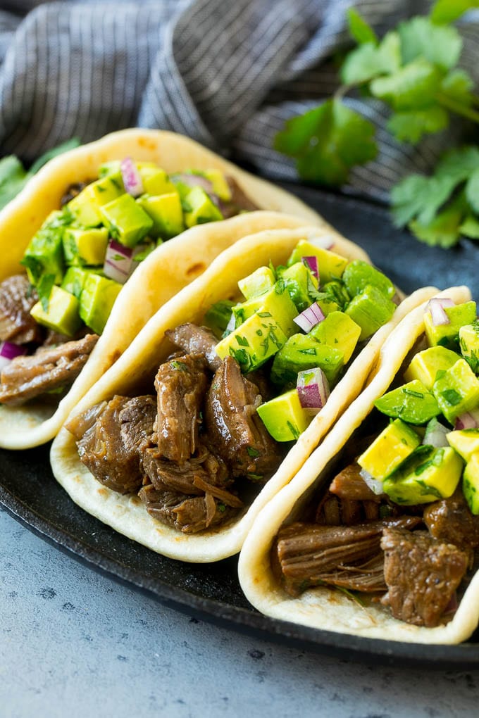 Slow cooker barbacoa tacos topped with avocado.